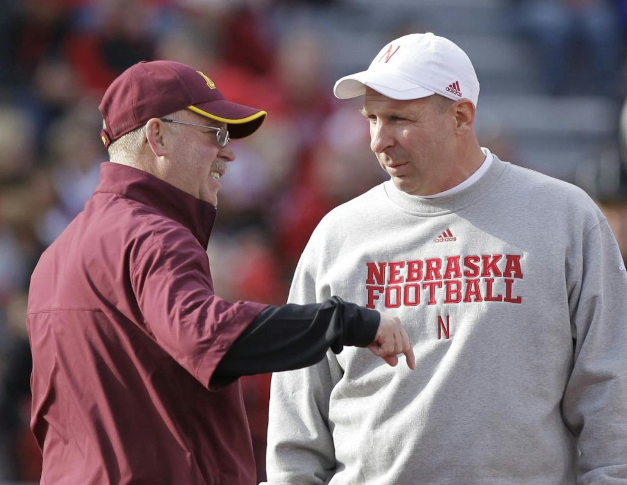 Gophers football coach Jerry Kill, left, chats with Bo Pelini. Pelini is now head coach at Youngstown State.