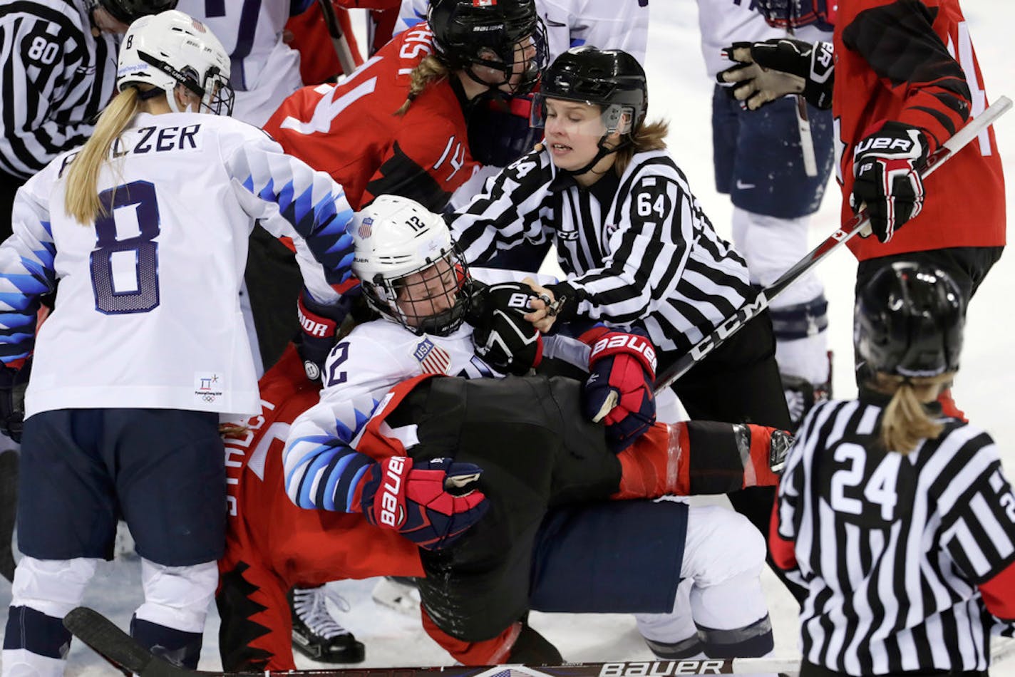 Official Jenni Heikkinen (64), of Finland, tries to separate Kelly Pannek (12), of the United States, and Laura Stacey (7), of Canada, as they scuffle during the third period of a preliminary round during a women's hockey game at the 2018 Winter Olympics in Gangneung, South Korea, Thursday, Feb. 15, 2018.