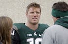 Michigan State quarterback Connor Cook, center, talks with team trainer Sally Nogle, left, and his father, Chris Cook, right, following an NCAA colleg