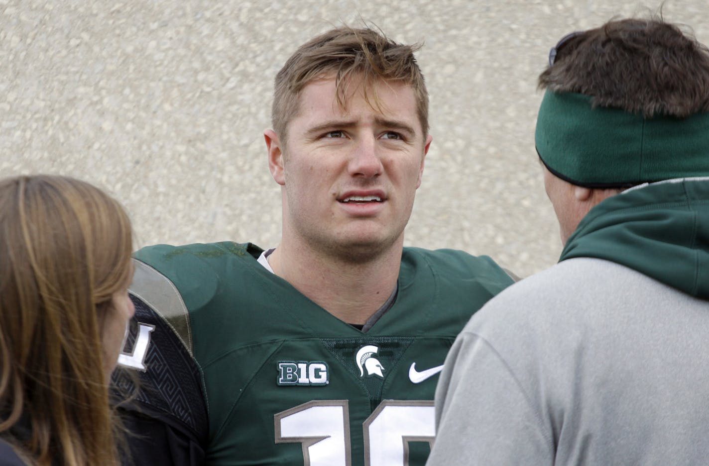 Michigan State quarterback Connor Cook, center, talks with team trainer Sally Nogle, left, and his father, Chris Cook, right, following an NCAA college football game against Maryland, Saturday, Nov. 14, 2015, in East Lansing, Mich. Michigan State won 24-7. (AP Photo/Al Goldis)