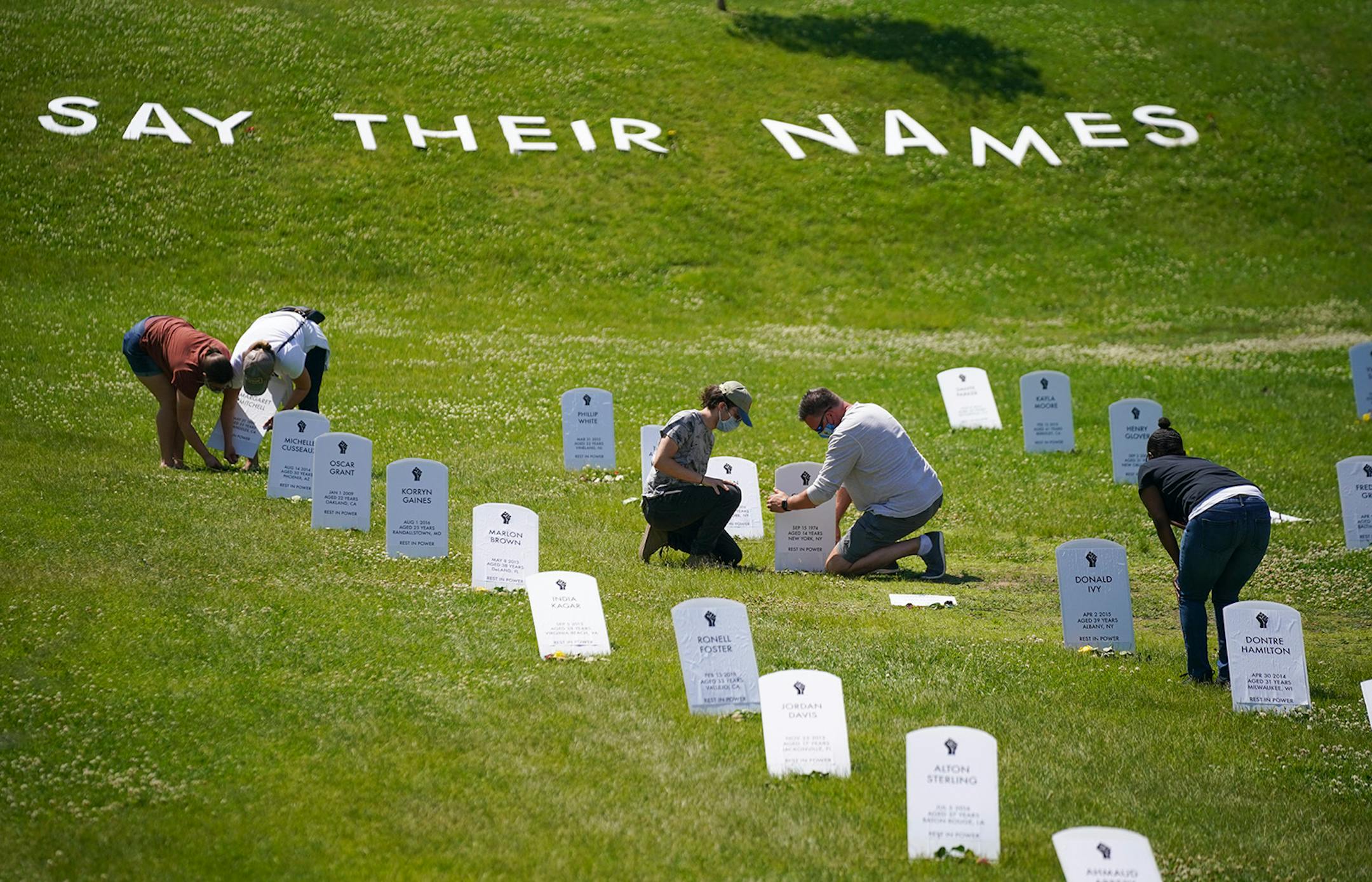 Johan Nielsen of Hudson, Wis., fixed a fallen headstone in the memorial for victims of police violence near E. 38th St, and Chicago Ave. S. Sunday afternoon. With him was Peter Wilhelmi. At left, Peter's mother, Susan Roeder and sister, Eleanor, were righting a headstone as well. They are from Stillwater.