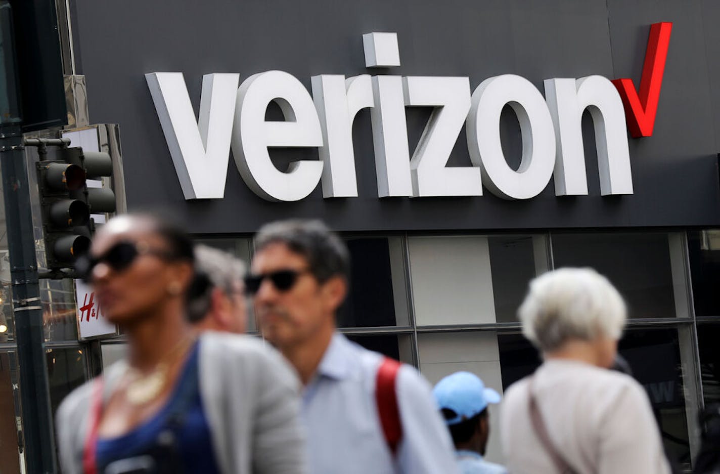 FILE- In this May 2, 2017, file photo, people walk past a Verizon store in Manhattan's midtown area, in New York. Verizon Communications Inc. reports financial earns on Friday, Oct. 25, 2019. (AP Photo/Bebeto Matthews, File)