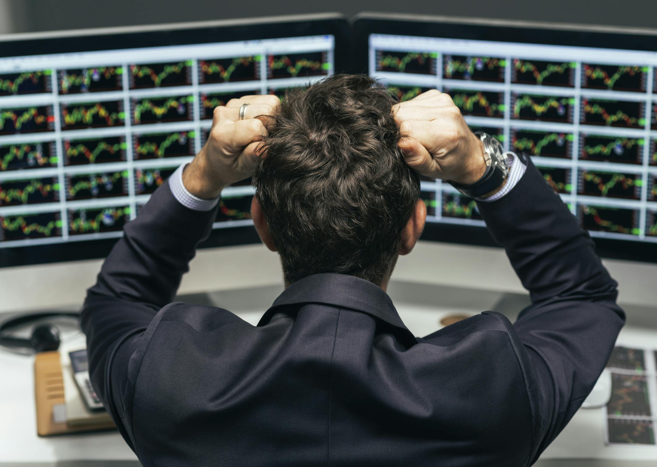 Stock trader tearing out his hair from despair, rear view