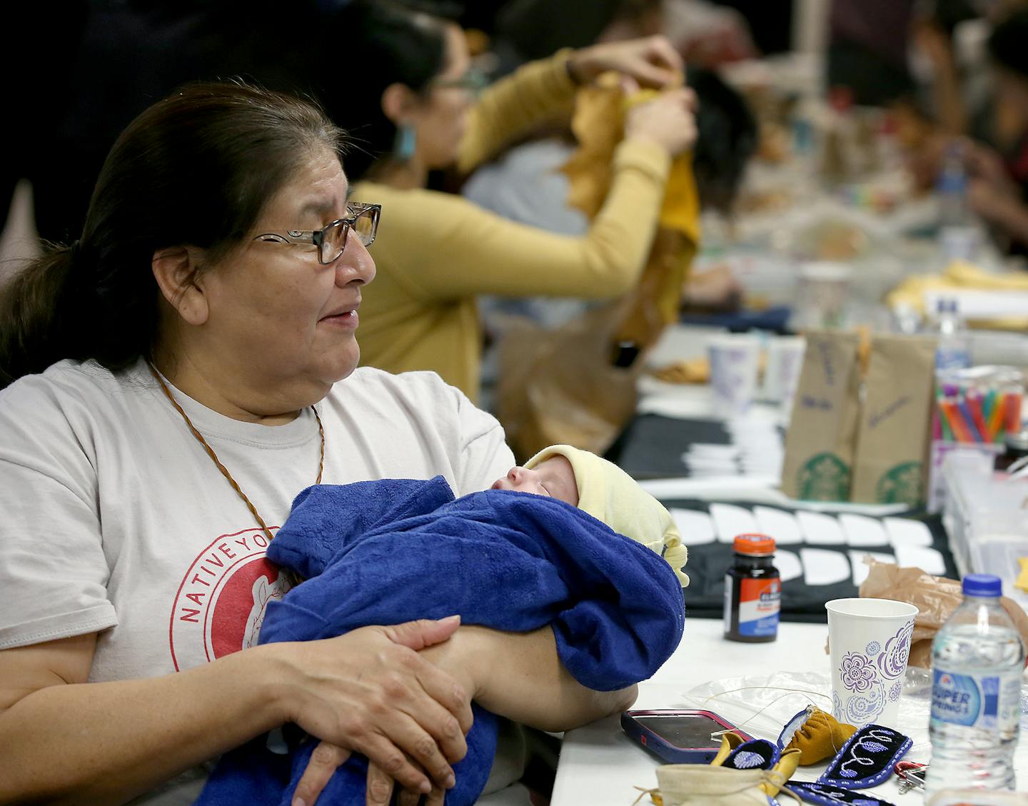 Eloise Gunmaker held a baby as the mother made moccasins at the American Indian Cultural Center. ] (ELIZABETH FLORES/STAR TRIBUNE) ELIZABETH FLORES &#x2022; eflores@startribune.com