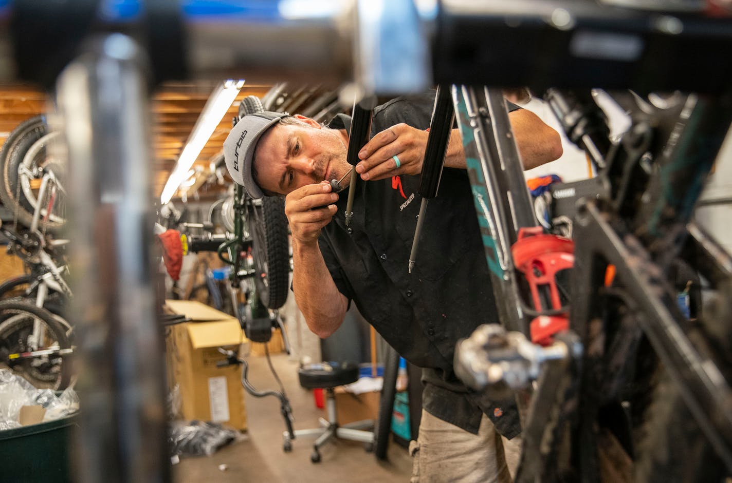 Ross Fraboni, the service manager at Ski Hut, worked on changing the travel in the suspension fork of a bike in the workshop on Thursday. ]