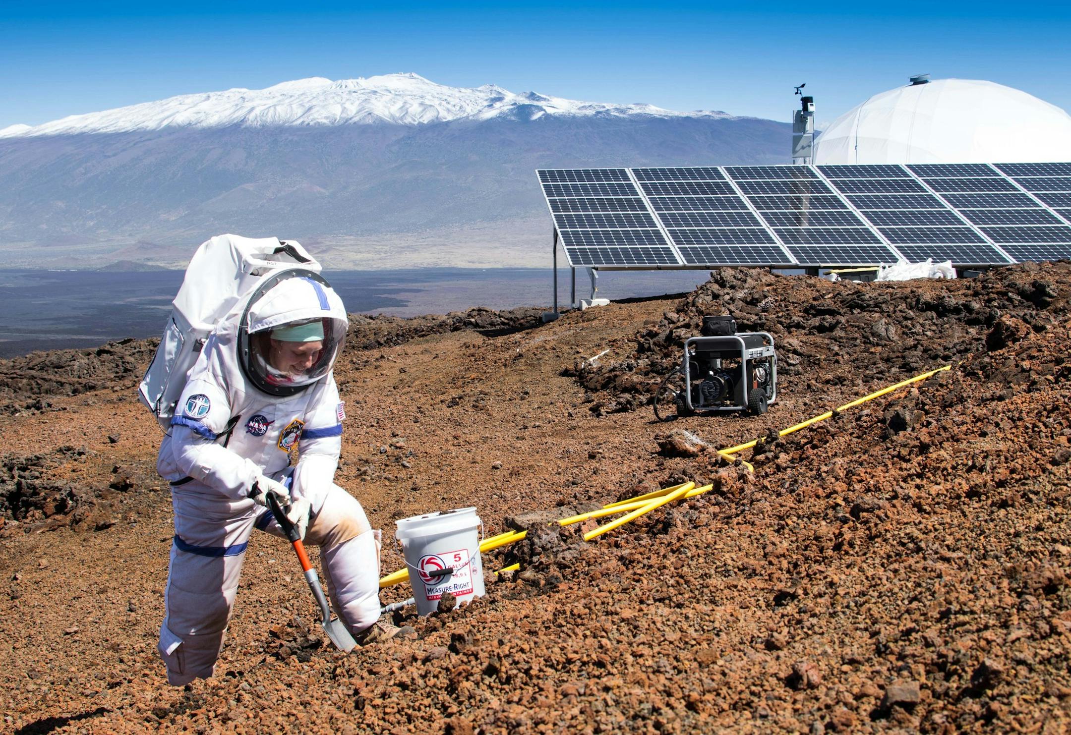 In this March 10, 2015, photo provided by the University of Hawaii at Manoa HI-SEAS Human Factors Performance Study, mission commander Martha Lenio collects a soil sample outside of the dome in which six scientists lived an isolated existence to simulate life on a mission to Mars, on the bleak slopes of dormant volcano Mauna Loa near Hilo on the Big Island of Hawaii. The scientists who took part of a human performance study funded by NASA, stepped outside the dome at 8,000 feet elevation to feel