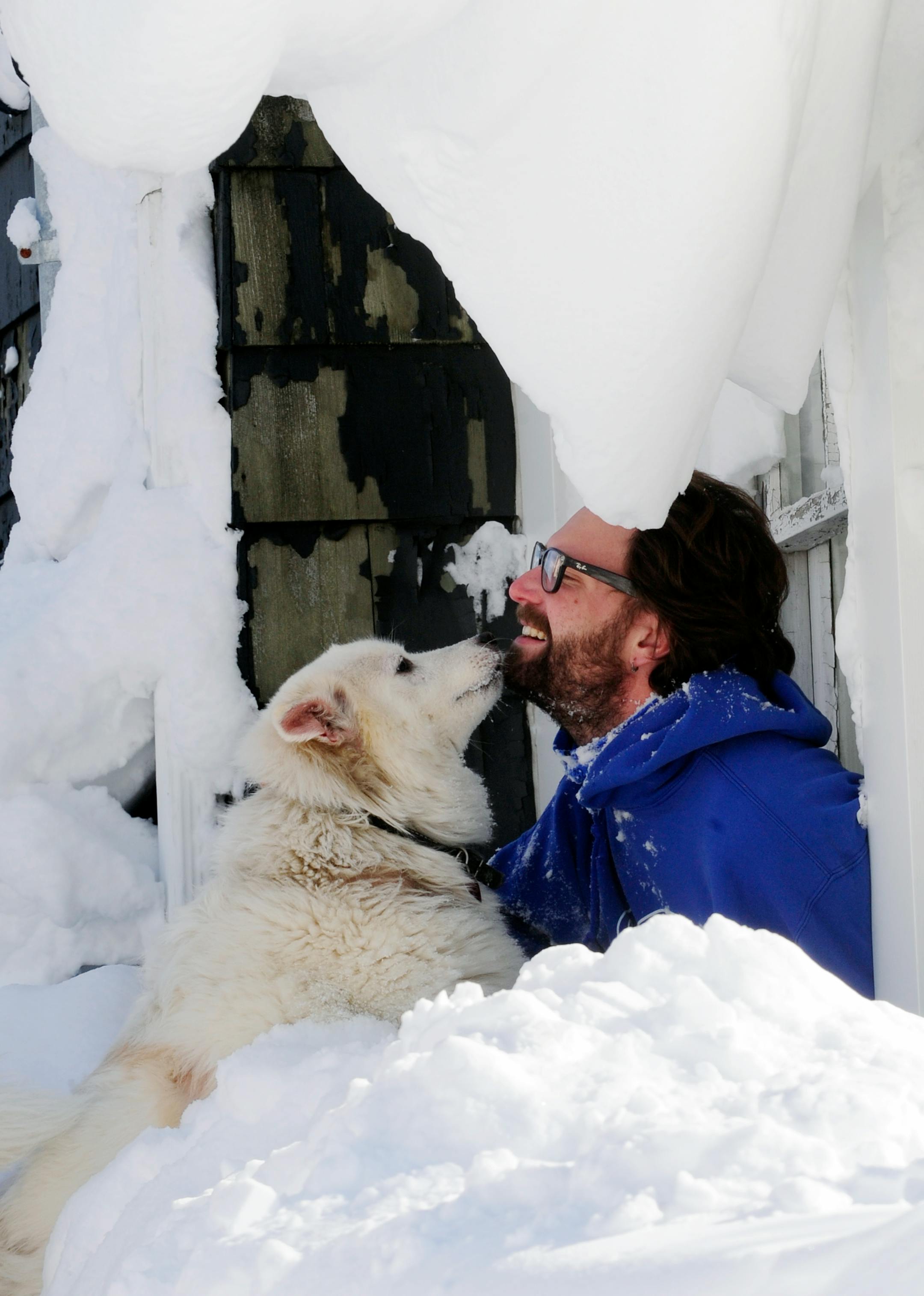 Steve Corbett opens his window under snow drifts and greets his neighbor's dog Wednesday, Nov. 19, 2014, on Central Ave in Lancaster, N.Y. A lake-effect snow storm dumped over five feet of snow in areas across Western New York. Another two to three feet of snow is expected s expected in the area, bringing snow totals to over 100 inches, almost a years' worth of snow in three days. (AP photo/Gary Wiepert)