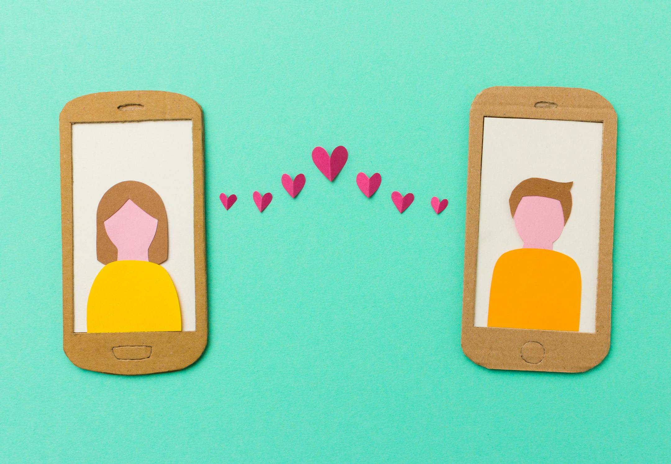 Online dating and mobile flirting concept - man and woman profile on smartphones connected with flying paper hearts