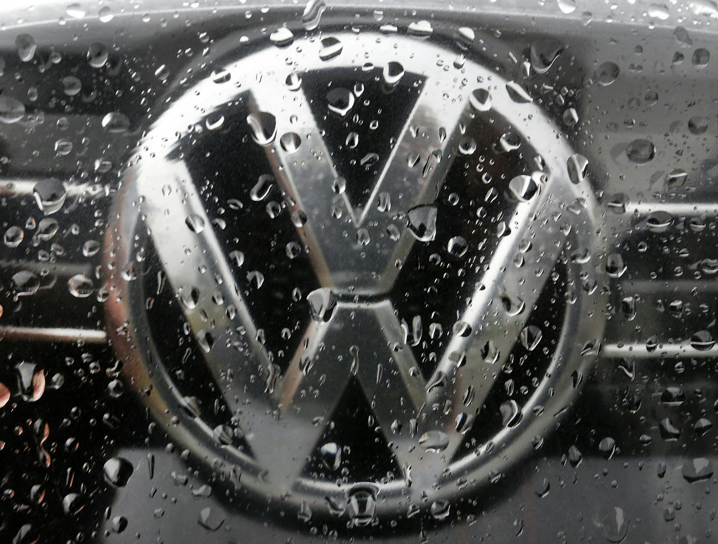 FILE - In this Nov. 18, 2016 file photo the Volkswagen logo is photographed through rain drops on a window in Frankfurt, Germany. Volkswagen has agreed to pay at least US$ 1.2 billion in buybacks and compensation to settle claims from U.S. owners of cars with larger diesel engines that the company rigged to cheat on emissions tests. The proposed settlement filed late Tuesday, Jan. 31, 2017 in U.S. District Court in San Francisco covers owners of some 75,000 Audi, Volkswagen and Porsche cars with