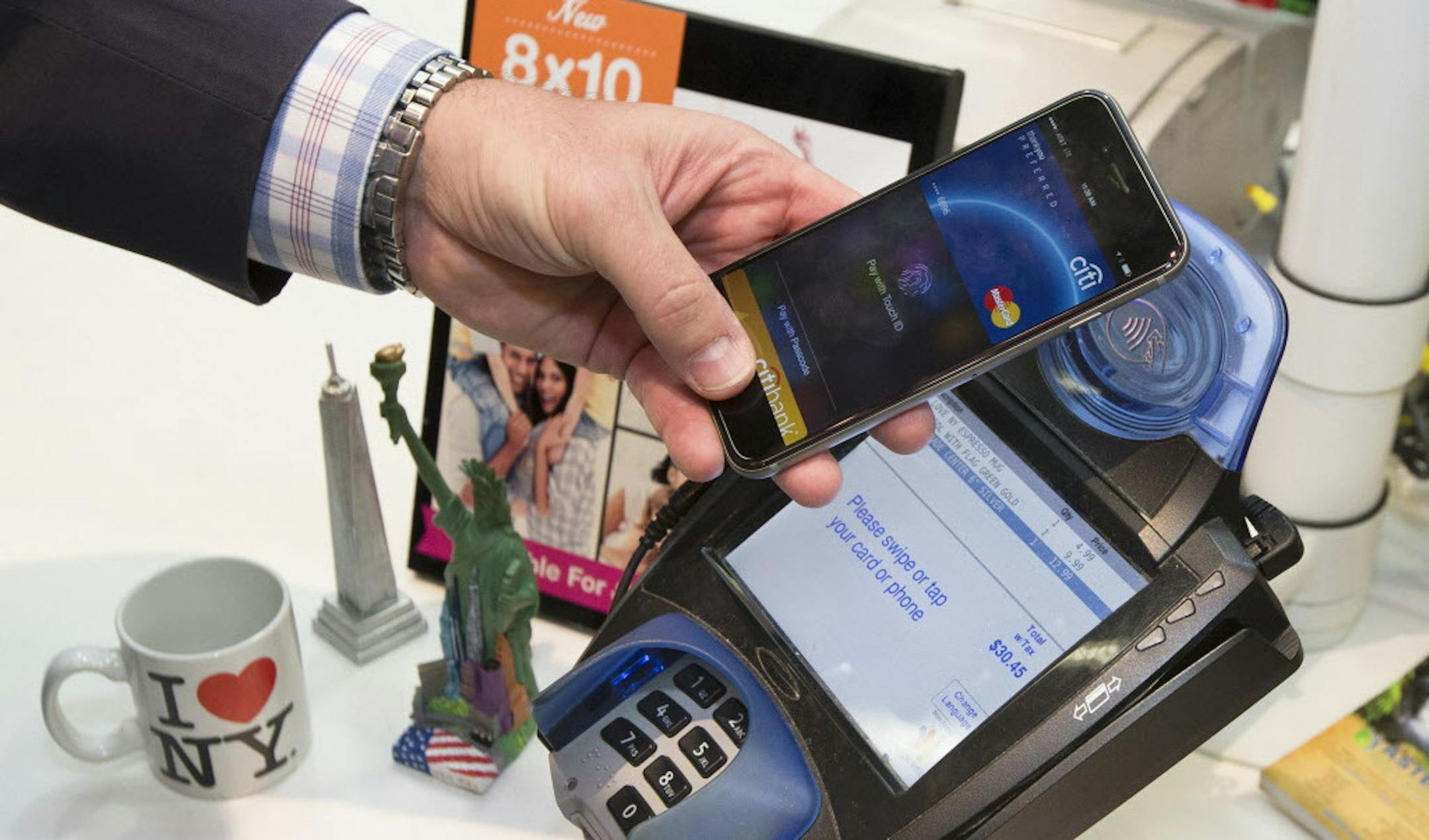 IMAGE DISTRIBUTED FOR MASTERCARD - A customer makes a purchase with a MasterCard using Apple Pay on the iPhone 6 at Walgreens in Times Square, Monday, Oct. 20, 2014, in New York. The service launched Monday. (John Minchillo/AP Images for MasterCard)