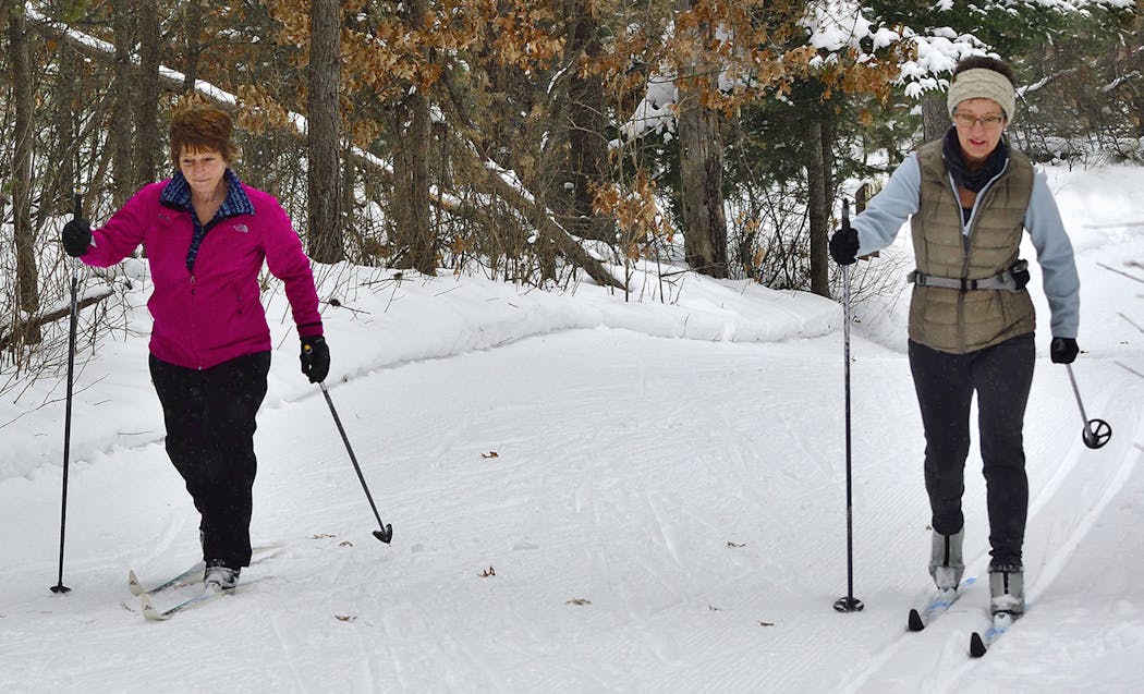 Two friends glide on cross-cuntry skis at the Northland Arboretum in Brainerd last Saturday. Many ski trails in the state are groomed to accommodate classic-style skiing as well as skate-skiing.