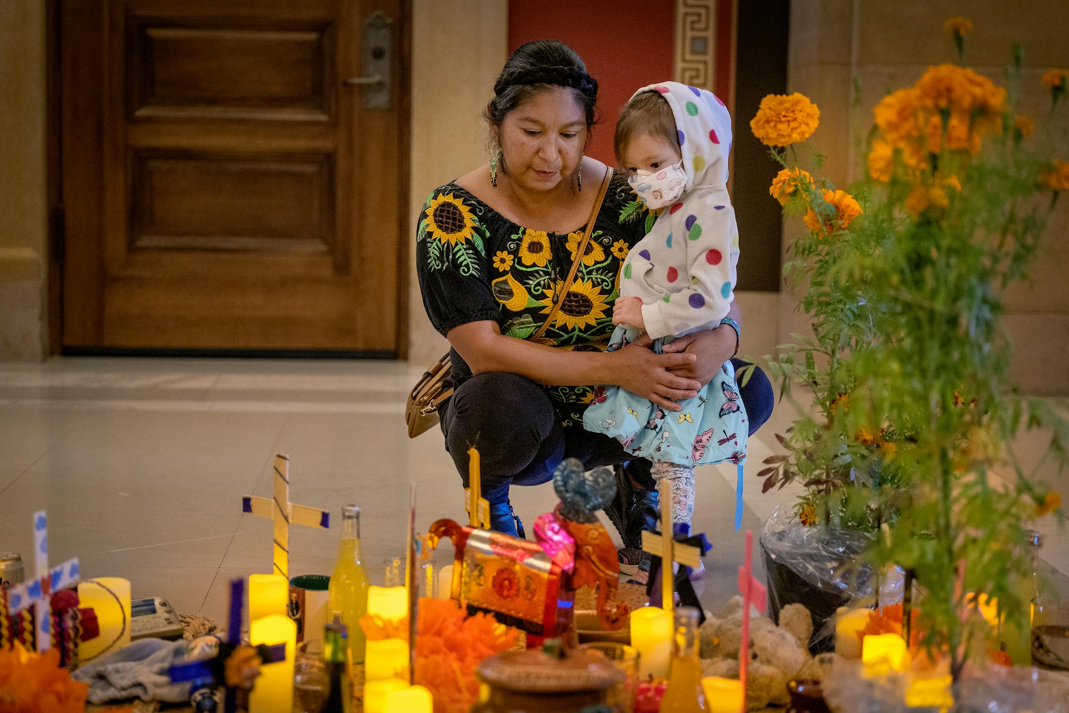 Erika Resendiz Alonso, and her daughter leave a flower as they visit the first ever "Altar de Muertos" or community altar for Days of the Dead at the Minnesota State Capitol in St. Paul, Minn., on Tuesday, Nov. 1, 2022.