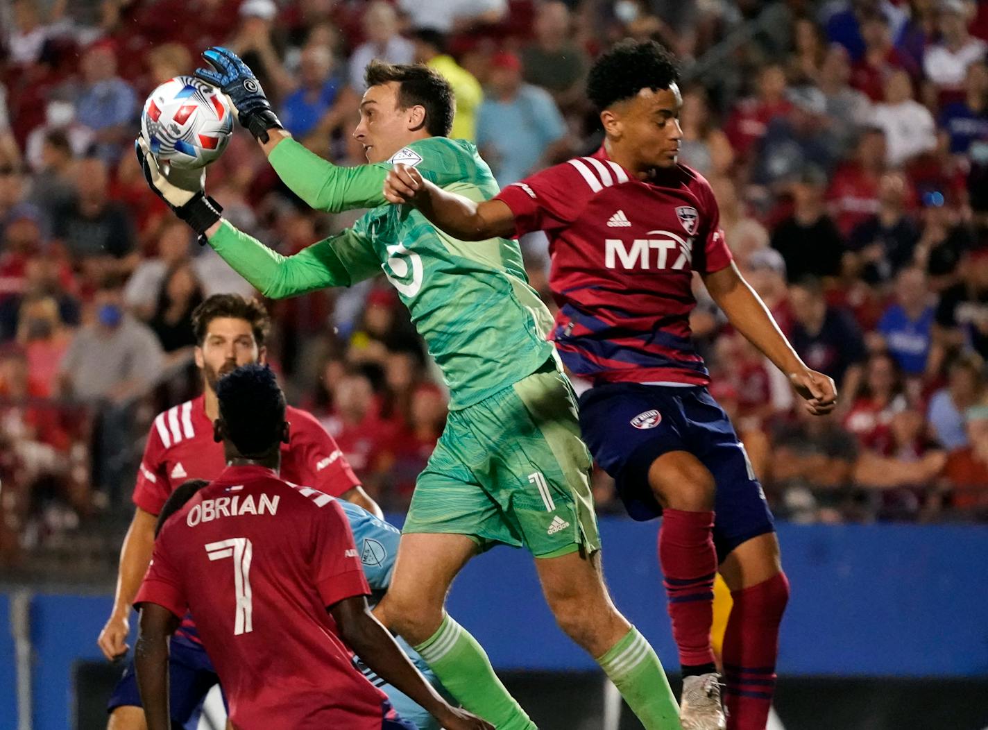 Minnesota United goalkeeper Tyler Miller (1) makes a save against FC Dallas midfielder Brandon Servania (obscured) as teammates Jader Obrian (7) and Matt Hedges, back left, look on during the second half of an MLS soccer match Saturday, Oct. 2, 2021, in Frisco, Texas. (AP Photo/LM Otero)