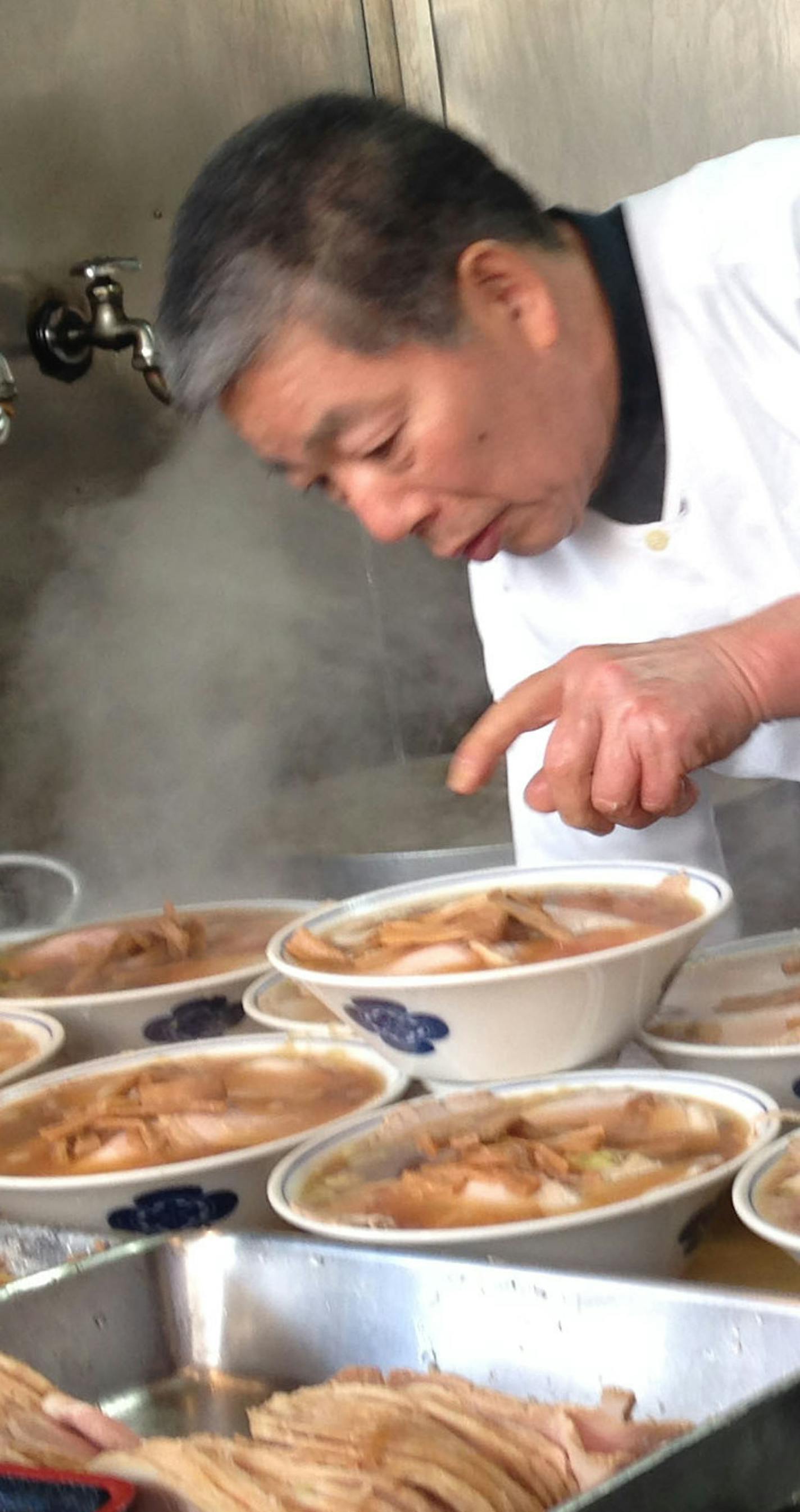 Bowls of ramen are built of layers of ingredients, as was evident at a Tokyo food stand where a cook prepared his dish for a long line of customers.