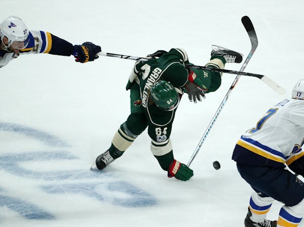 Minnesota Wild center Mikael Granlund (64) gets tripped up by St. Louis Blues left wing David Perron (57) while skating with the puck in the second pe