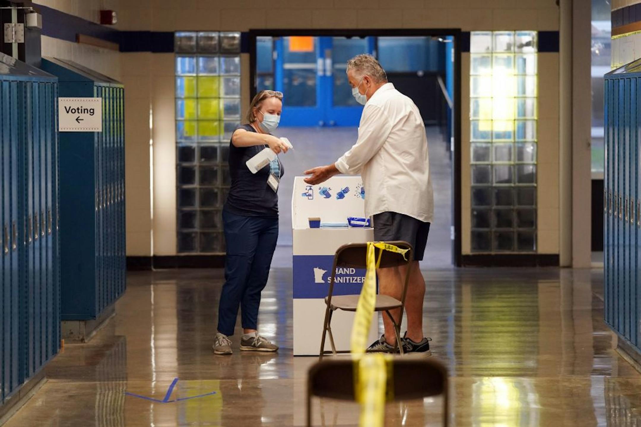 Election judge Maura Trout gave a spray of hand sanitizer to voter Tom Dunnwald as he he arrived to cast his ballot Tuesday morning at Northeast Middle School in Minneapolis.