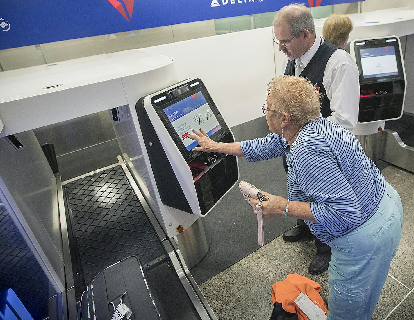 Delta Airlines ticket agent Chris Morris helped guide traveler through their new self-service bag drop machine at Minneapolis-St. Paul International Airport (MSP), Monday, June 19, 2017 in Bloomington, MN. The self-service bag drop machine is a $600,000 investment that allows customers to quickly, securely and easily check their own bags. Each machine will be equipped to test facial recognition technology to match customers with their passport photos through identification verification, a first