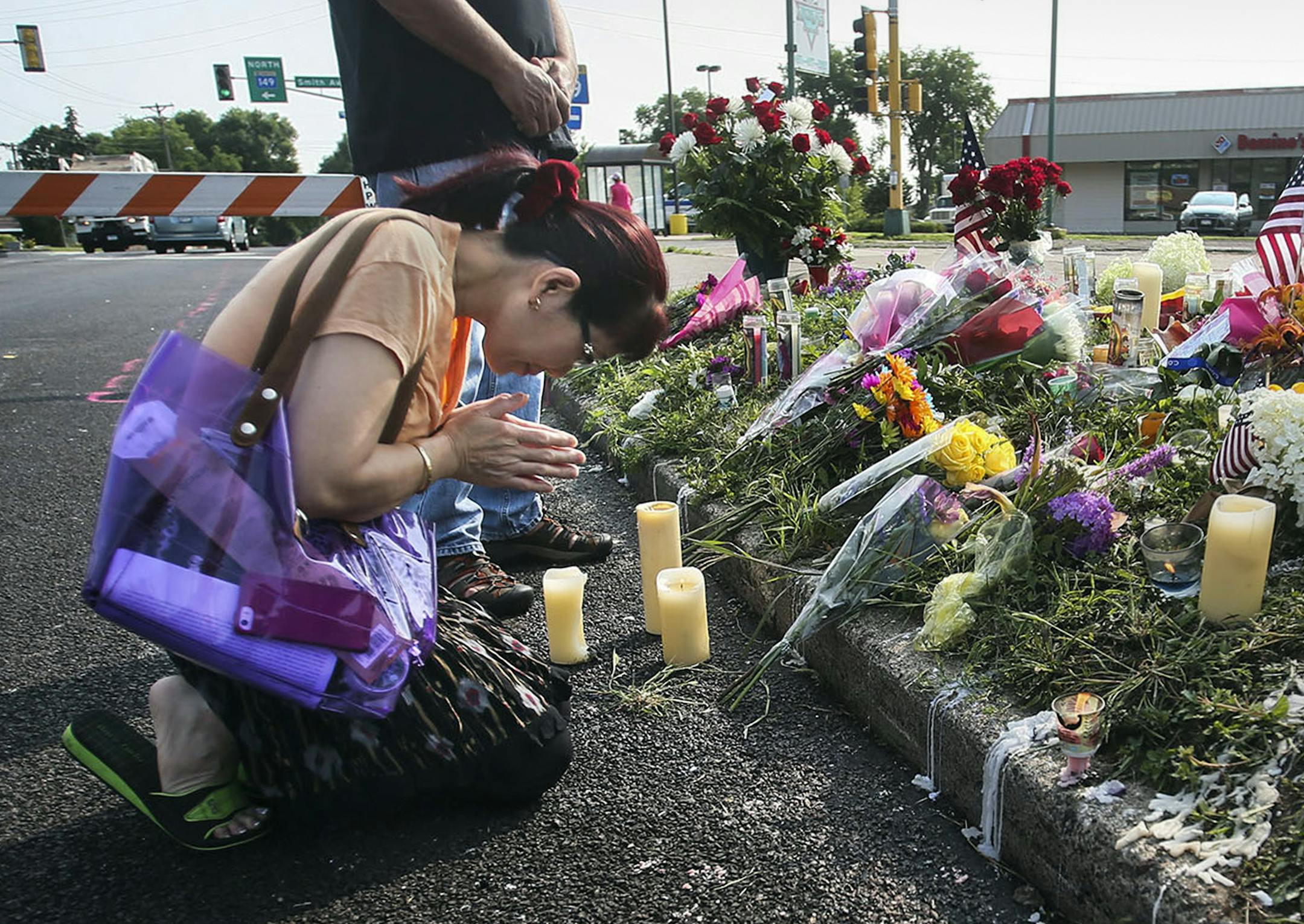 A day after the shooting death of Mendota Heights police officer Scott Patrick, a Memorial is growing near Smith Ave. and Dodd Road, near his slaying Thursday, July 31, 2014, in W. St. Paul, MN. Here, Kieu Nguyen of St. Paul bows her head in prayer at the Memorial site. Nguyen, orginally from Vietnam, said she decided to be late for work to visit the site. "I'm really so sad about it," adding, "in my culture we pray for them."] (DAVID JOLES/STARTRIBUNE) djoles@startribune The day after the shoot