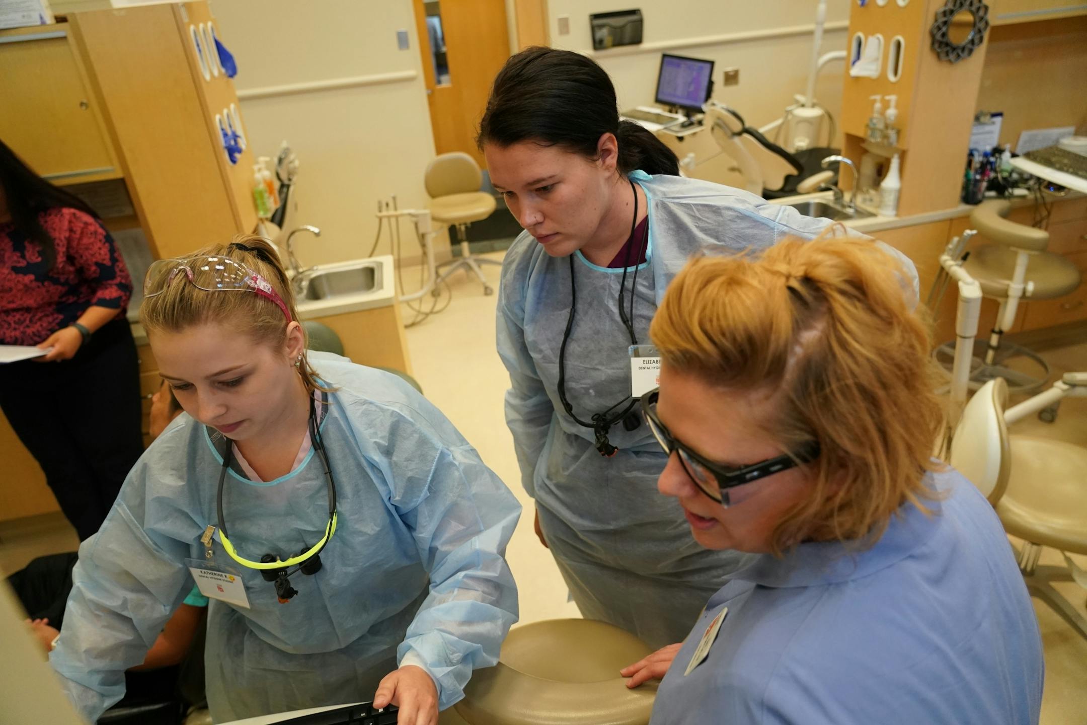 Second year dental students Katherine Rolek (left) and Elizabeth Wilder listened to former Argosy University and current Century College faculty advisor Kami Burgess inside Community Dental Care in Maplewood. The two students were part of a group of 35 who continued their education and training through Century College after the abrupt closing of Argosy Univeristy.