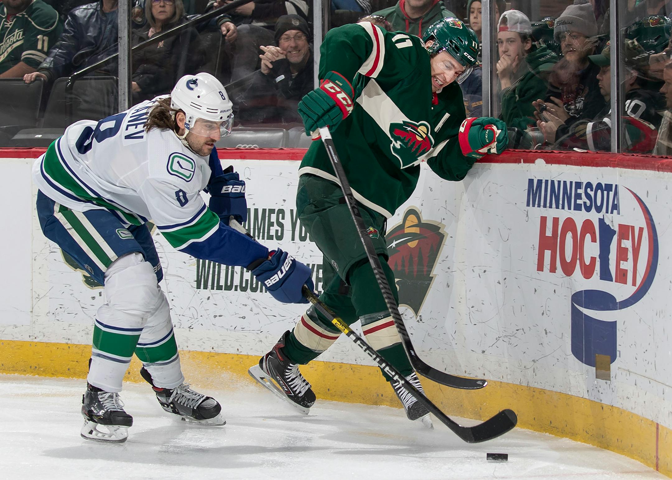 Christopher Tanev (8) of the Vancouver Canucks and Zach Parise (11) of the Minnesota Wild fought for the puck in the first period.