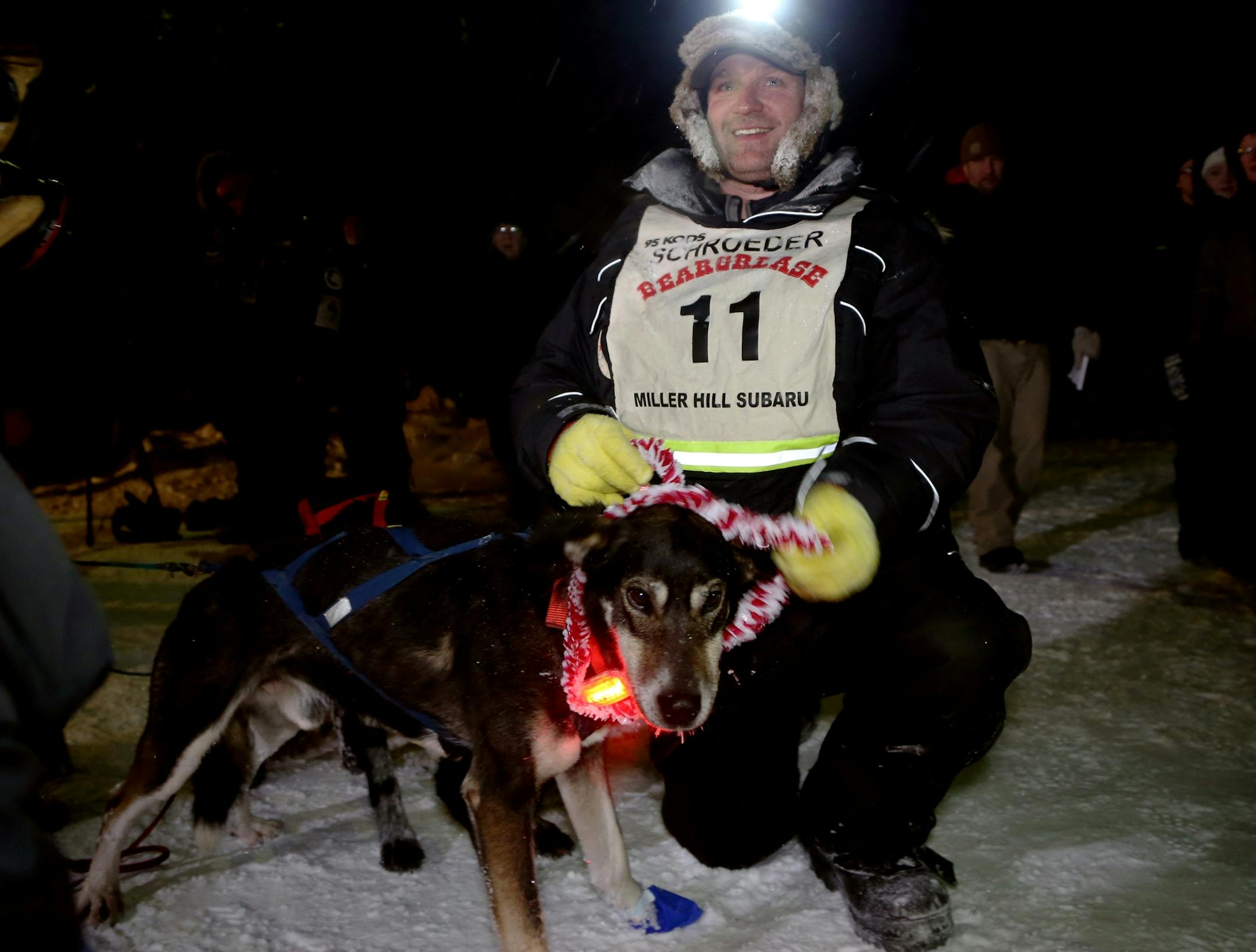 Musher Nathan Schroeder, of Warba, Minn., puts a ring of flowers around the neck of his lead dog, after they had reached the finish line at Billy's Bar just before 6 a.m., Wednesday, Feb. 3, 2016, in Rice Lake, near Duluth, Minn., to win the nearly 400-mile-long John Beargrease Sled Dog Marathon. (Paul M. Walsh/WDIO-TV via AP)