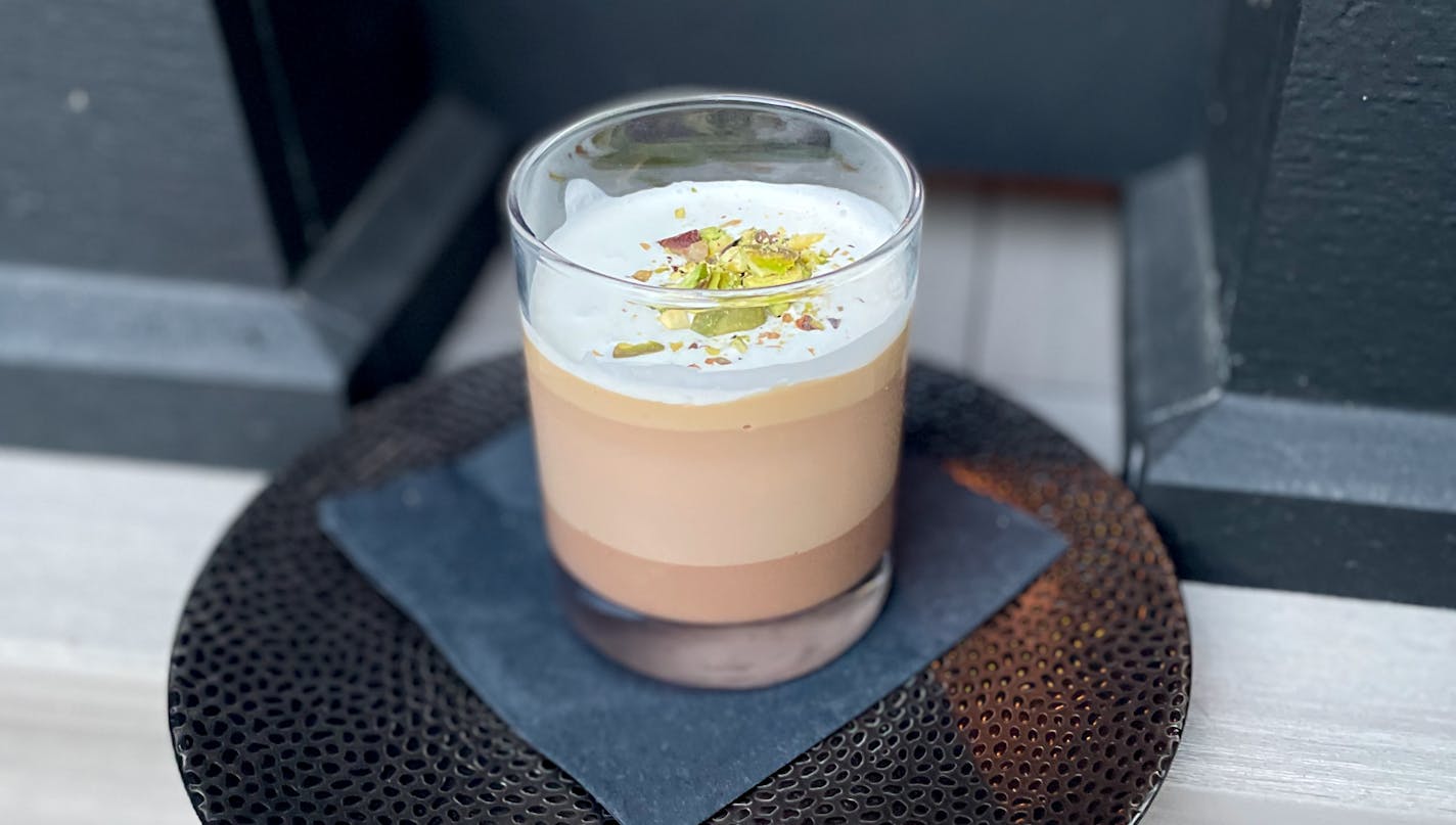 Forepaugh's chocolate budino is served in a clear glass that shows off the layers of dark and milk chocolate with an airy dollop of creme fraiche and a garnish of crunched up green pistachios.