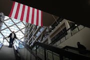 People pass beneath the American flag Tuesday, March 5, 2024 at the Hennepin County Government Center in Minneapolis. The parking garage that serves t