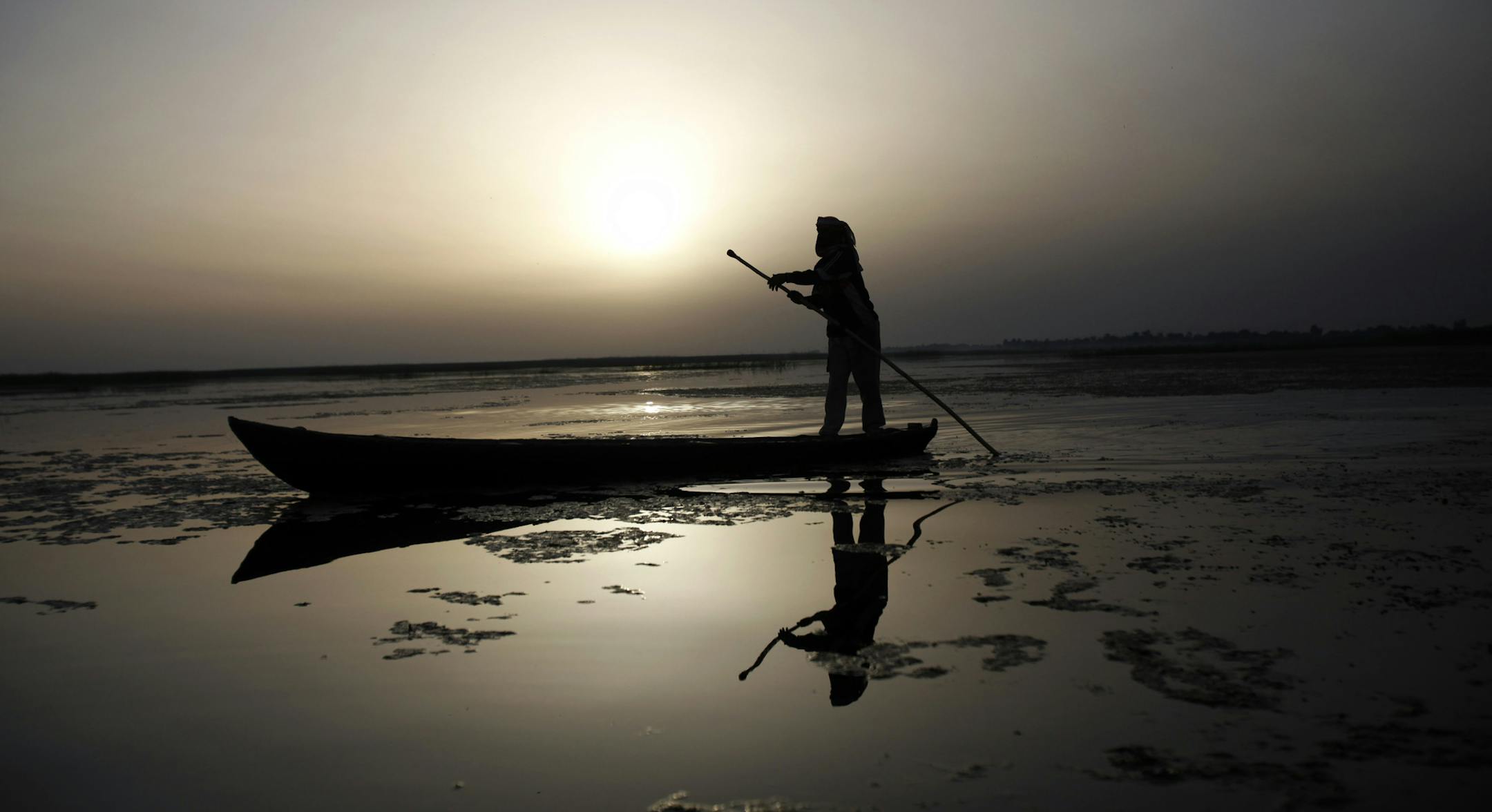 In this photo taken Friday, March 27, 2009, a fisherman navigates his boat in Hor al-Hammar in southern Iraq. A severe drought is threatening Iraq's southern marshes, the traditional site of the biblical Garden of Eden, just as the region was recovering from Saddam Hussein's draining of its lakes and swamps to punish a political rebellion. (AP Photo/Hadi Mizban)