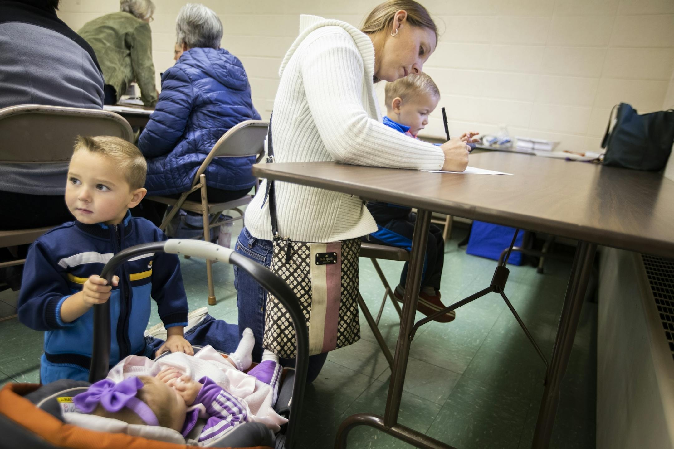 Mary Menne, with her children Peter, from left, 4, Josephine, five months, and Isaac, 2, fills out her ballot at St. Joseph's Catholic Church Parish Center in Henderson.