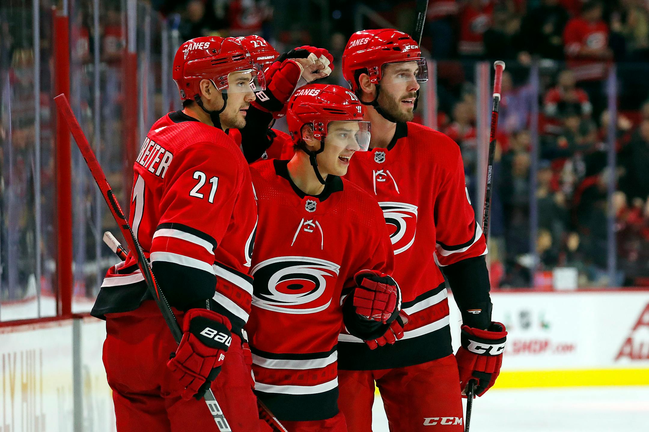 Carolina's Sebastian Aho (20) celebrates his goal against the Wild with teammates Nino Niederreiter (21) and Joel Edmundson, right, during the second period