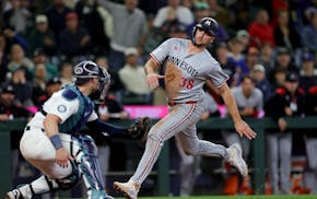 Mariners catcher Mitch Garver, left, prepares to tag out the Twins' Matt Wallner at home to keep the score tied in the 10th inning Saturday night in S