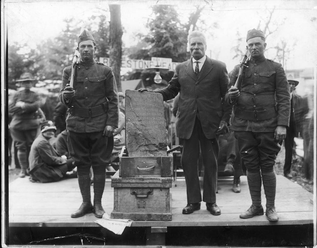 Olof Ohman, in tie, and the Kensington Runestone are flanked by armed guards at an exhibition in about 1929. Ohman said he found the buried stone on his Minnesota farm.