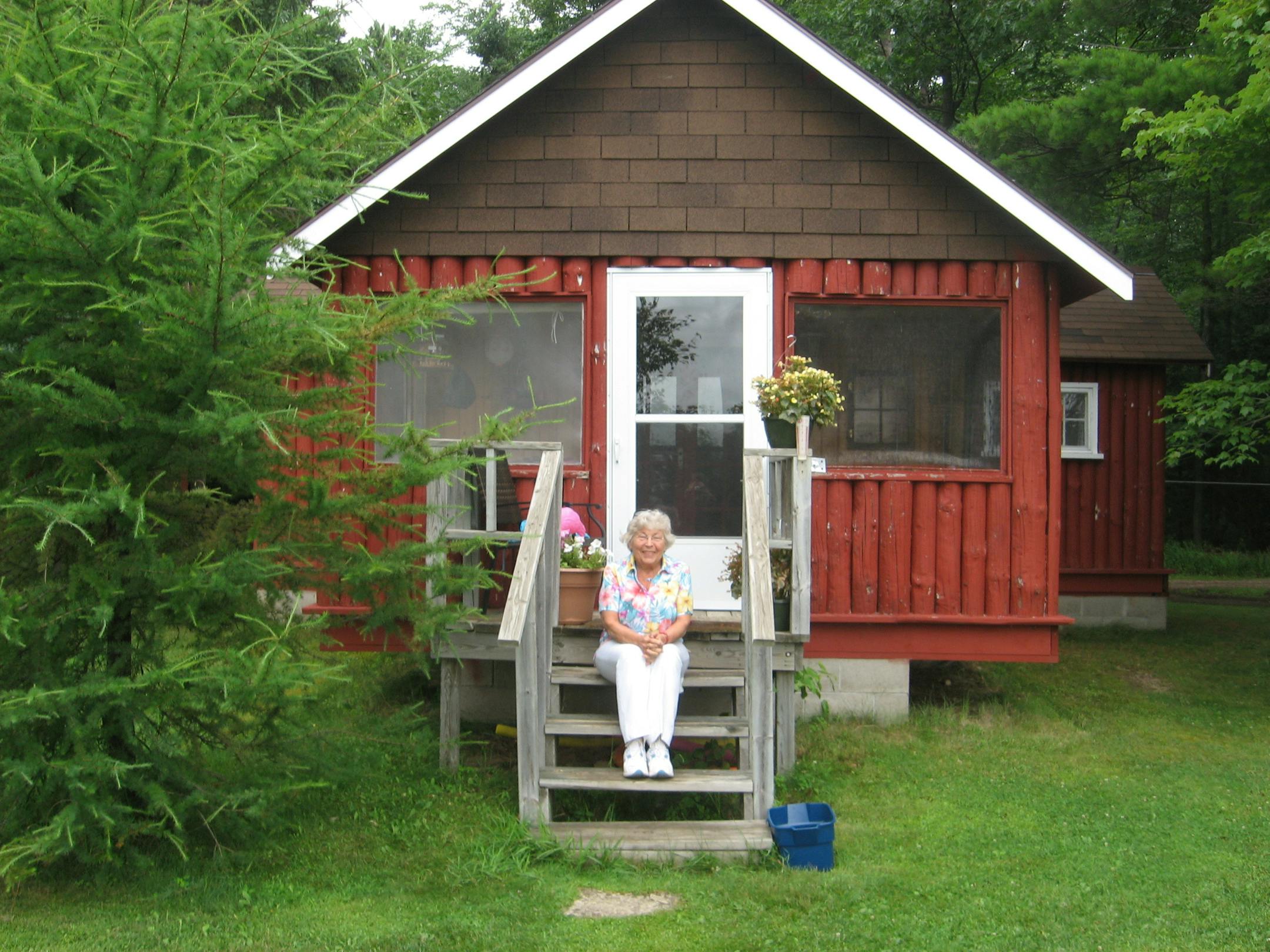 Carolyn Engstrand sits on the steps of her privately owned cabin, a property she parceled out from the resort she once owned with her late husband.
