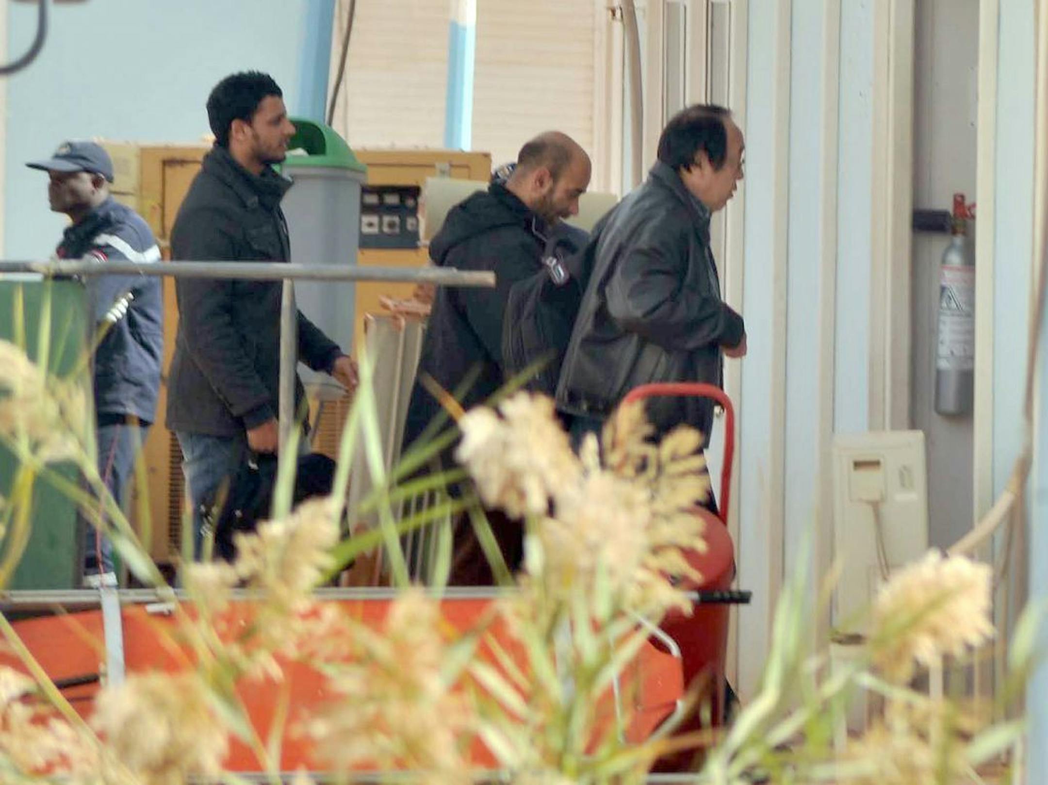 An unidentified person, right, is followed by Algerian officials as they enter a morgue in Ain Amenas Algeria Monday, Jan. 21, 2013, where the bodies of the persons killed during the hostage situation at the gas plant are gathered. At least 81 people have been reported dead, including 32 Islamist militants, after a bloody, four-day hostage situation at Algeria's remote Ain Amenas natural gas plant.