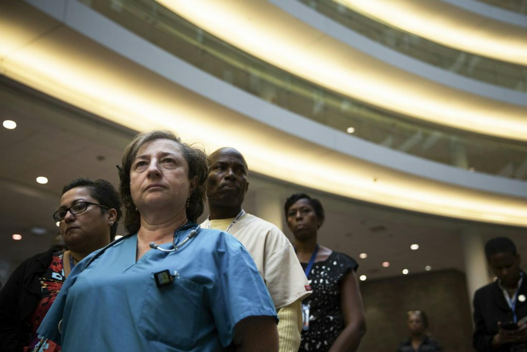 Hospital staff and onlookers watch as New York City Mayor Bill de Blasio speaks during a news conference at Bellevue Hospital Center in New York, Oct. 26, 2014. The governors of New York and New Jersey on Sunday stood by their decision to require medical workers who had contact with Ebola patients in West Africa into quarantine, despite deep concerns about the impact it might have on fighting the epidemic and the lack of clarity about exactly how the plan would work.