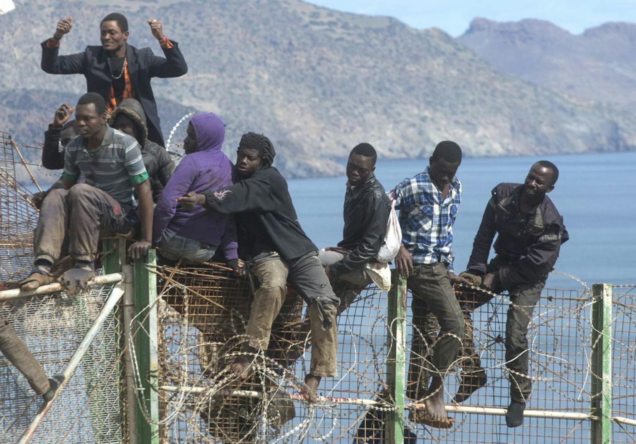 Sub-Saharan migrants sit on top of a metallic fence that divides Morocco and the Spanish enclave of Melilla on Thursday, April 3, 2014.