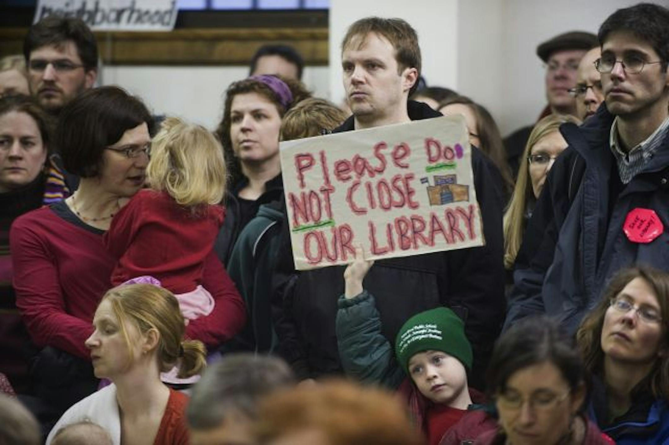 Moses Ranweiler, 6, standing in front of his father Christopher Ranweiler, held his sign high at a meeting with St.Paul Mayor Chris Coleman in the Hamline-Midway Library basement auditorium.