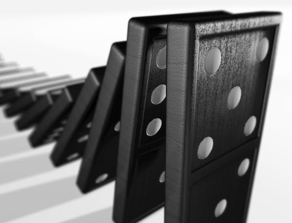 A stack of dominoes falling. 3D rendering with depth of field blur.