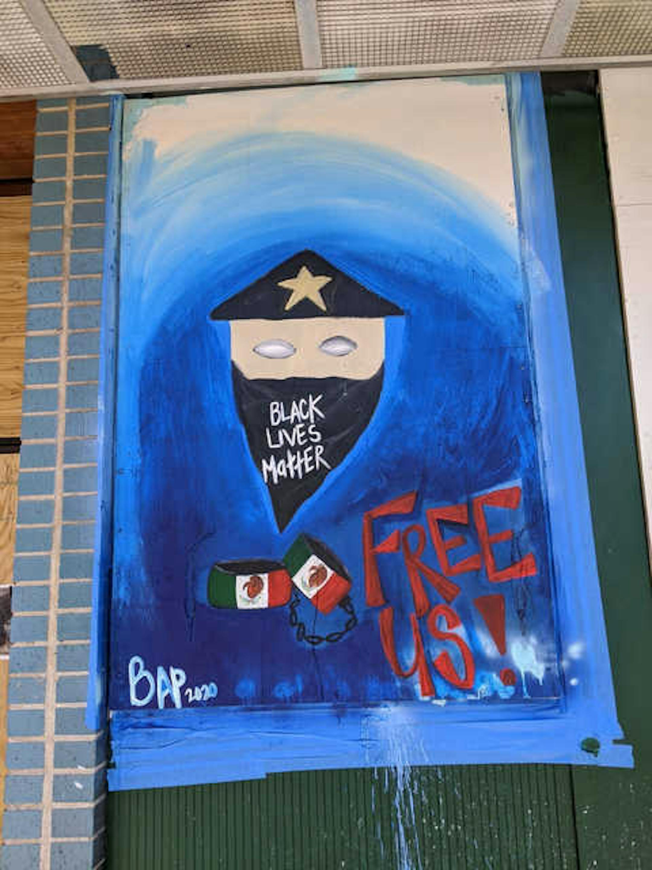 Artist @artby_b_ap's paints a mural on Green Machine, 2409 Nicollet Ave., that calls for re-envisioning the police department and handcuffs with the Mexican flag on them that "symbolize freeing the kids at the border," she said.