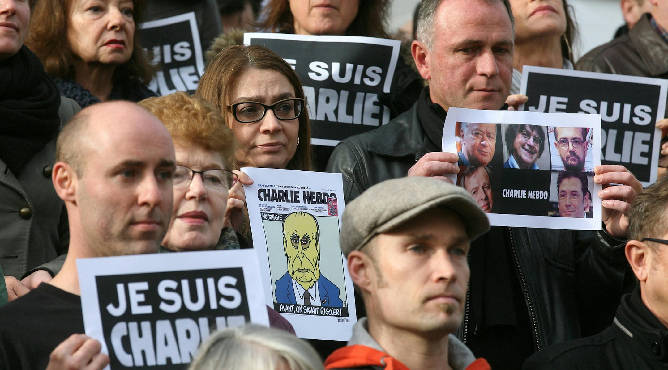 People hold up placards reading &#xec;I am Charlie&#xee; after workers installed a giant poster for victims of the shooting at the satirical newspaper Charlie Hebdo, on the Cannes Festival Palace, in Cannes, southeastern France, Friday, Jan.9, 2015. 12 peop[e were killed on Jan. 7 in a terrorist attack at the Charlie Hebdo headquarters in Paris. (AP Photo/Lionel Cironneau) ORG XMIT: MIN2015010917492009 ORG XMIT: MIN1501091800041221