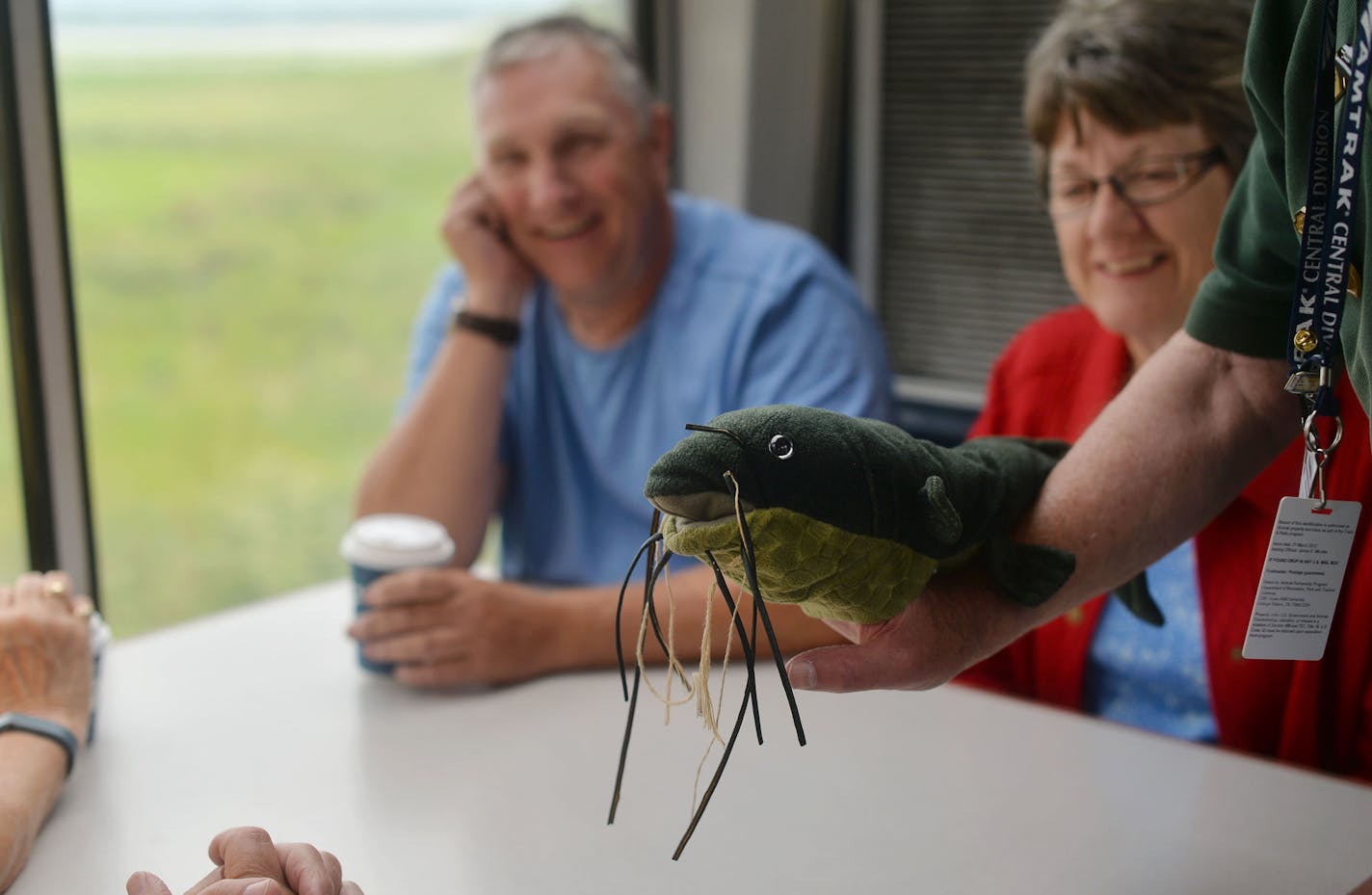 From left, Jim and Sally Muegge, both of Nebraska, smiled as Volunteer Master Ranger Corps Gary Freseman displayed and made jokes with a Catfish puppet, displaying The Mississippi National River and Recreational Area's mascot, Freddy, as part of the Trails and Rails program on the Amtrak Train that departed from Union Depot in St. Paul, Minn. and went to Chicago, Illinois, on Monday July 27, 2015. ] RACHEL WOOLF &#xb7; rachel.woolf@startribune.com