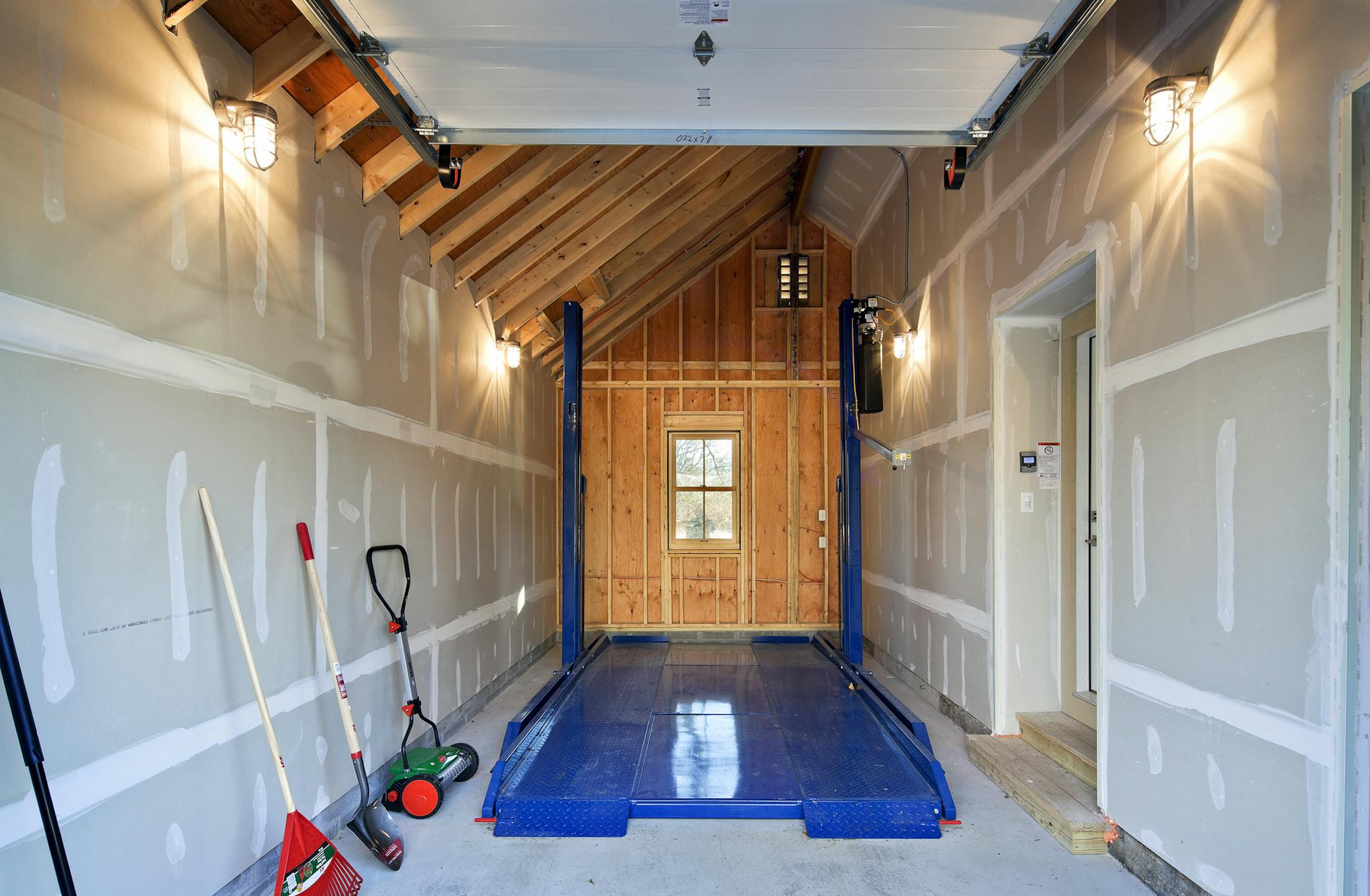 A steel hydraulic lift raises and lowers the top car. The roof has a ridge beam and rafters to create more interior space.