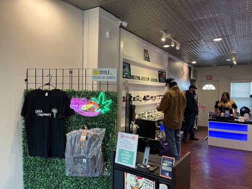 Alex Skym and Deedra Perron help a customer at DNA Dispensary in St. Paul. Beyond cannabis products, there are t-shirts and bags for sale.