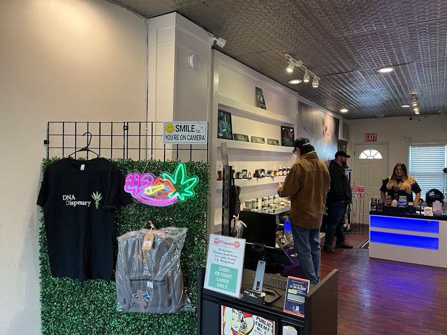Alex Skym and Deedra Perron help a customer at DNA Dispensary in St. Paul. Beyond cannabis products, there are t-shirts and bags for sale.