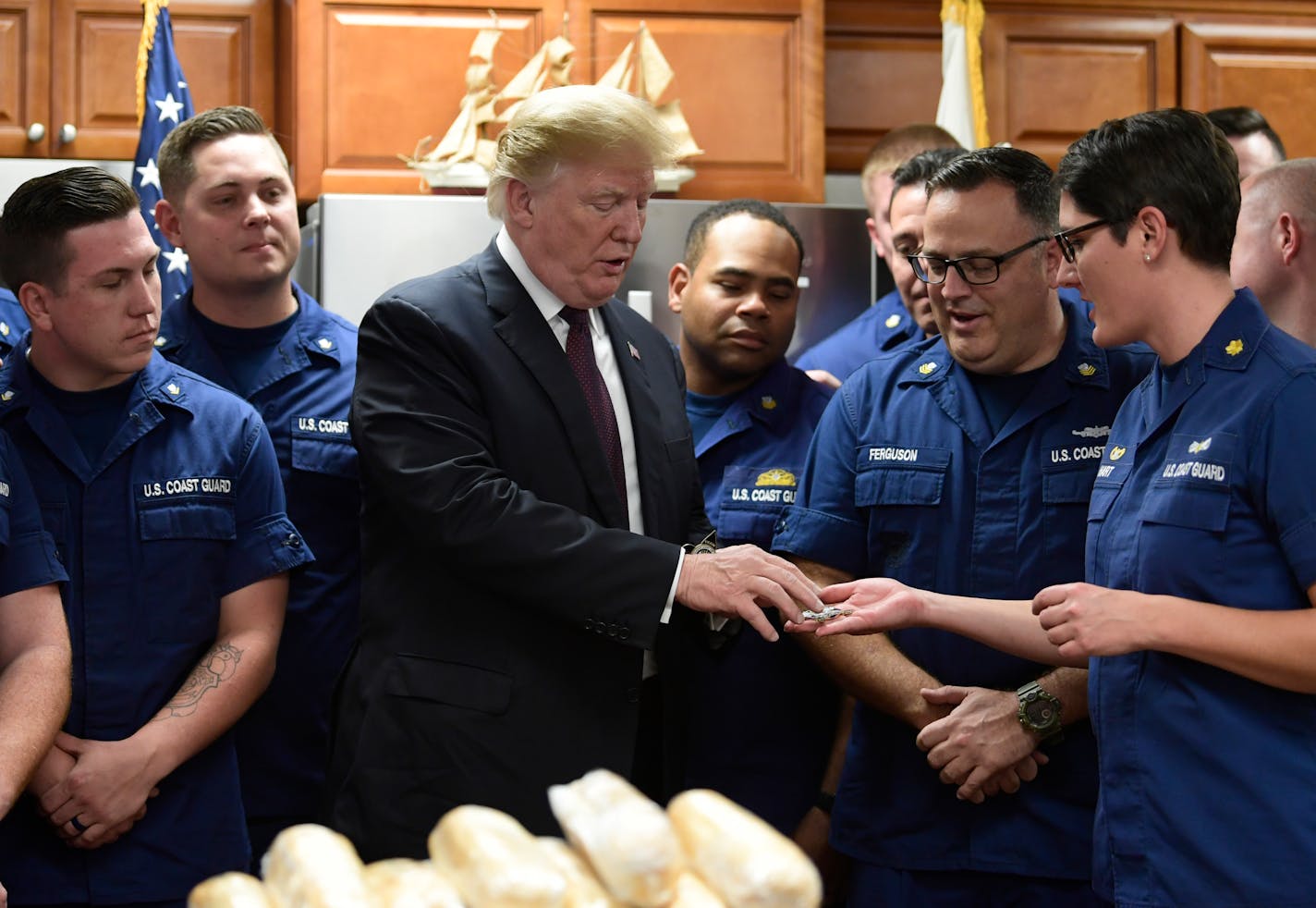 President Donald Trump is presented with a challenge coin as he meets with members of the U.S. Coast Guard stationed at United States Coast Guard Station Lake Worth Inlet in Riviera Beach, Fla., on Thanksgiving Day, Thursday, Nov. 22, 2018. (AP Photo/Susan Walsh)