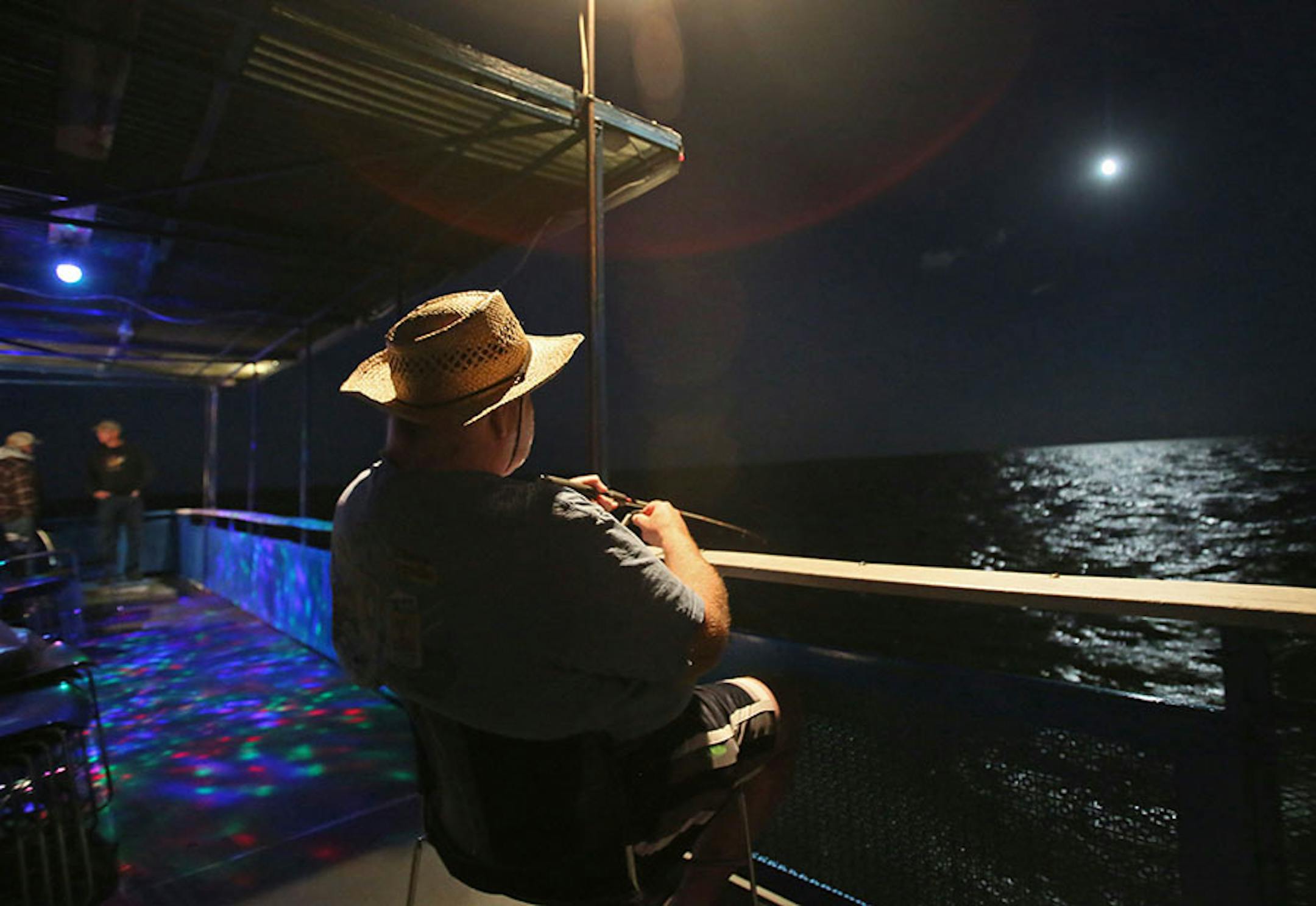 Fishermen David Hill of Brooklyn Park fishes by moon light and disco light on the Twin Pines Resort boat Wednesday, July 29, 2015, during an evening excursion on Lake Mille Lacs.