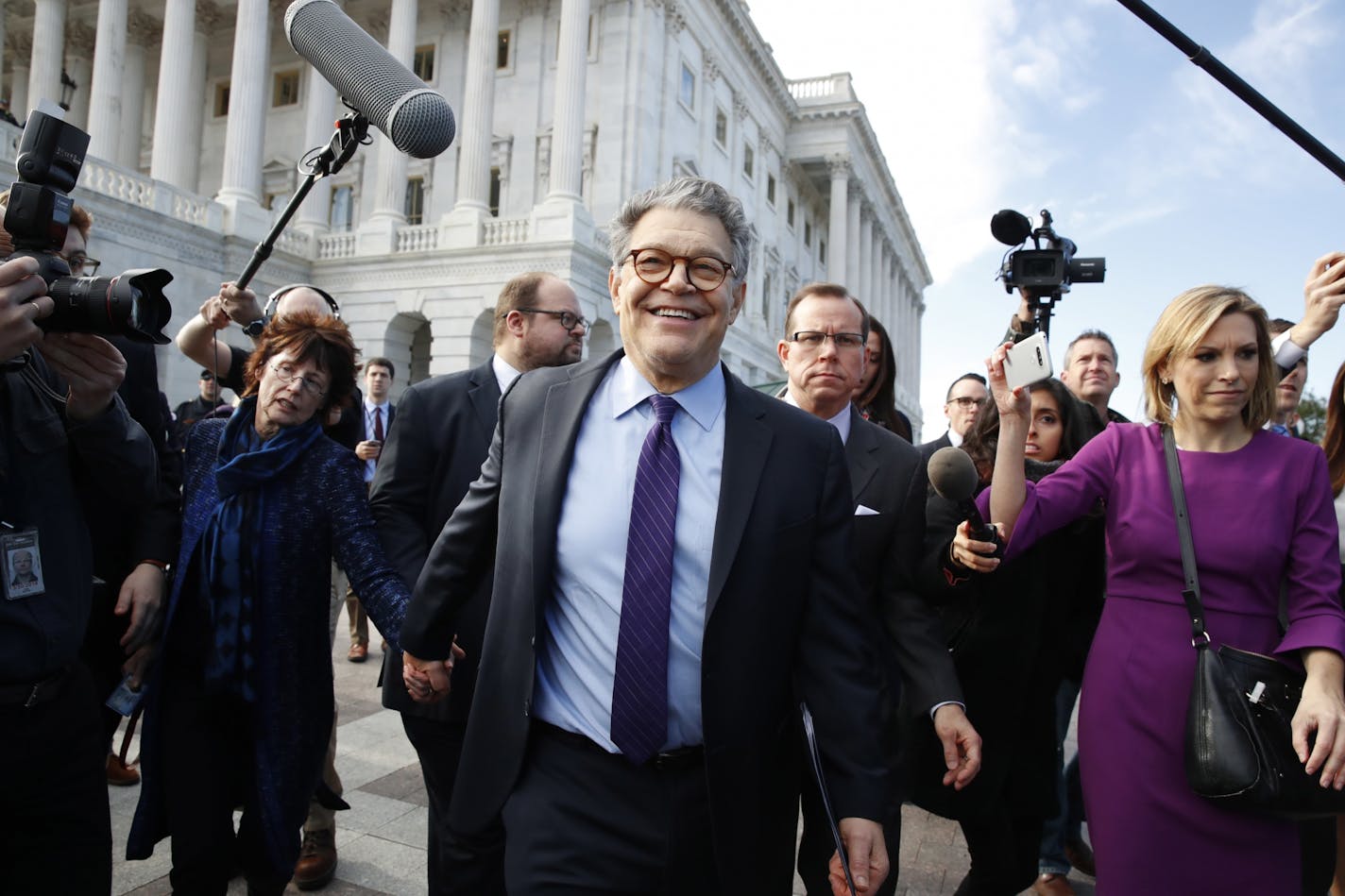 Sen. Al Franken, D-Minn., center, held hands with his wife, Franni Bryson, as he left the Capitol after announcing that he will resign in the coming weeks.