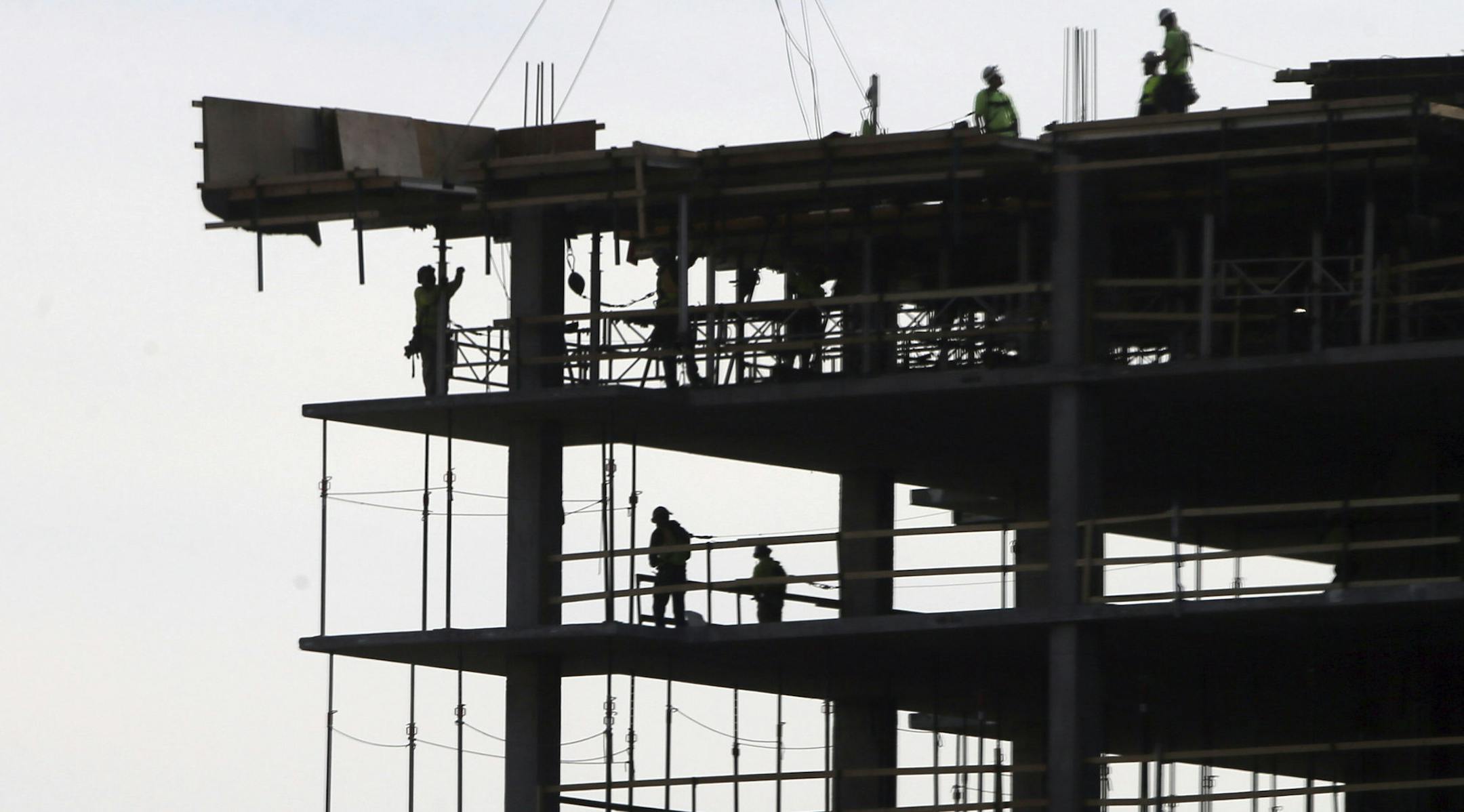 Work continues on a construction project Monday, March 30, 2020, in Minneapolis. An executive stay at home order was issued by Minnesota Gov. Tim Walz for non-essential businesses in an effort to slow down the coronavirus in the state. The new coronavirus causes mild or moderate symptoms for most people, but for some, especially older adults and people with existing health problems, it can cause more severe illness or death. (AP Photo/Jim Mone)
