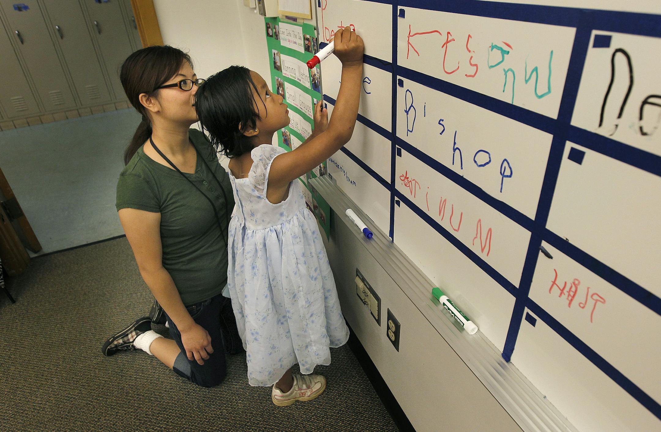 Pre-school teaching assistant Kia Vang, left, watched as Poe Tha Puh wrote her name on a board before class started at Eastern Heights Elementary School, Tuesday, July 9, 2013 in St. Paul, MN.