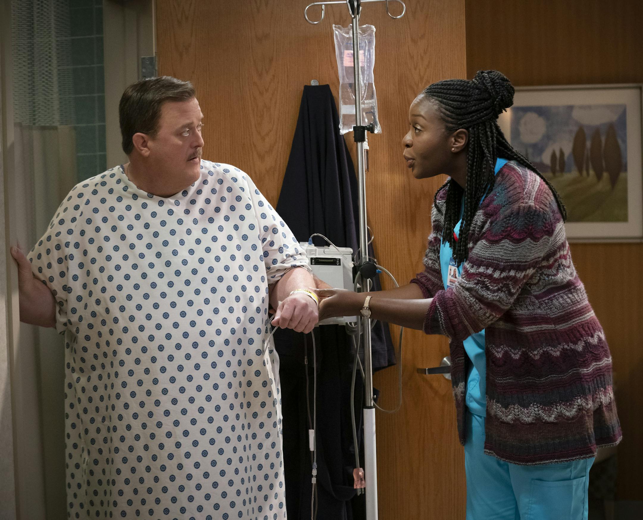 This image released by CBS shows Billy Gardell as Bob, left, and Folake Olowofoyeku as Abishola in a scene from "Bob Hearts Abishola," a comedy about a nurse and the former cardiac patient who pursues her. (Sonja Flemming/CBS via AP)